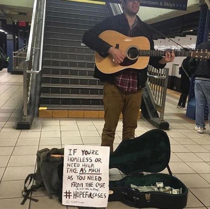 Auf dem Schild neben dem Mann steht: "Wenn du ein Obdachloser bist oder Geld brauchst, nimm alles, was du brauchst, aus dem Gitarrenkoffer."