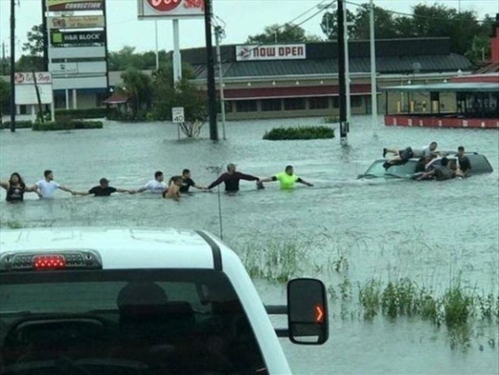 Some people formed a human chain to save a family trapped in a car during a flood.