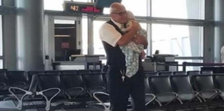 Un empleado del aeropuerto ayuda a una mama en viaje sola a calmar al pequeño hijo que llora.
