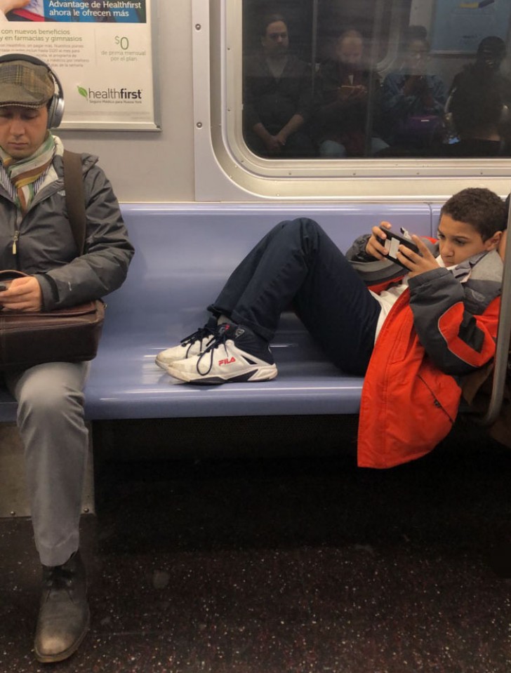 De jongen zat in de metro, met zijn voeten op de stoelen. Ondertussen speelde hij, zich niets aantrekkend van het ongemak dat hij veroorzaakte bij de andere mensen die moesten staan.