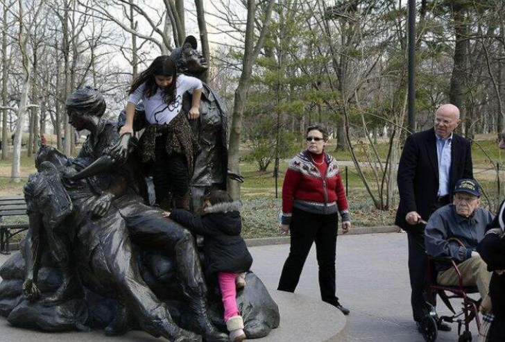 7. Des parents qui laissent leurs enfants "jouer" sur un monument à la mémoire des femmes de la guerre du Vietnam, sous les yeux des anciens combattants