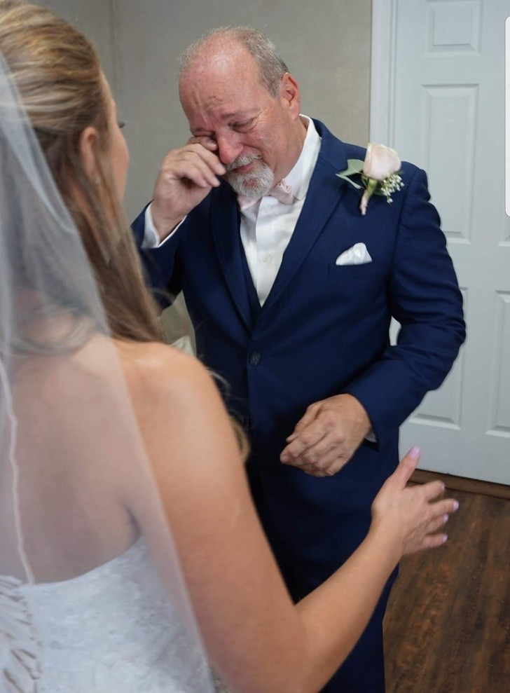 Le père est ému par la vue de la robe de mariée de sa fille cadette.