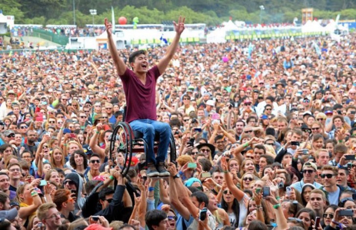 12. El público de este festival sostiene un joven sobre la silla de ruedas, para permitirle de ver de cerca el aspecto de su banda preferida.