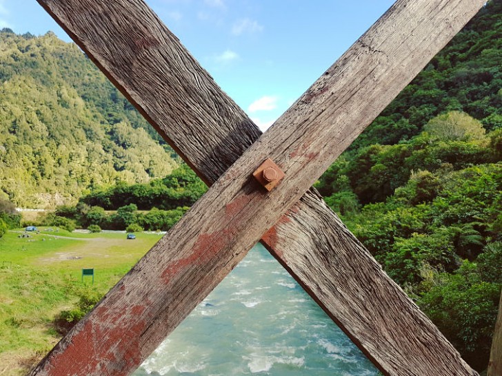 Cette barrière en bois semble diviser parfaitement le paysage vert de la couleur des eaux en contrebas.