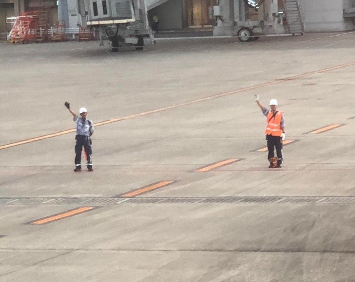 9. Gli addetti dell'aeroporto salutano l'aereo in partenza.