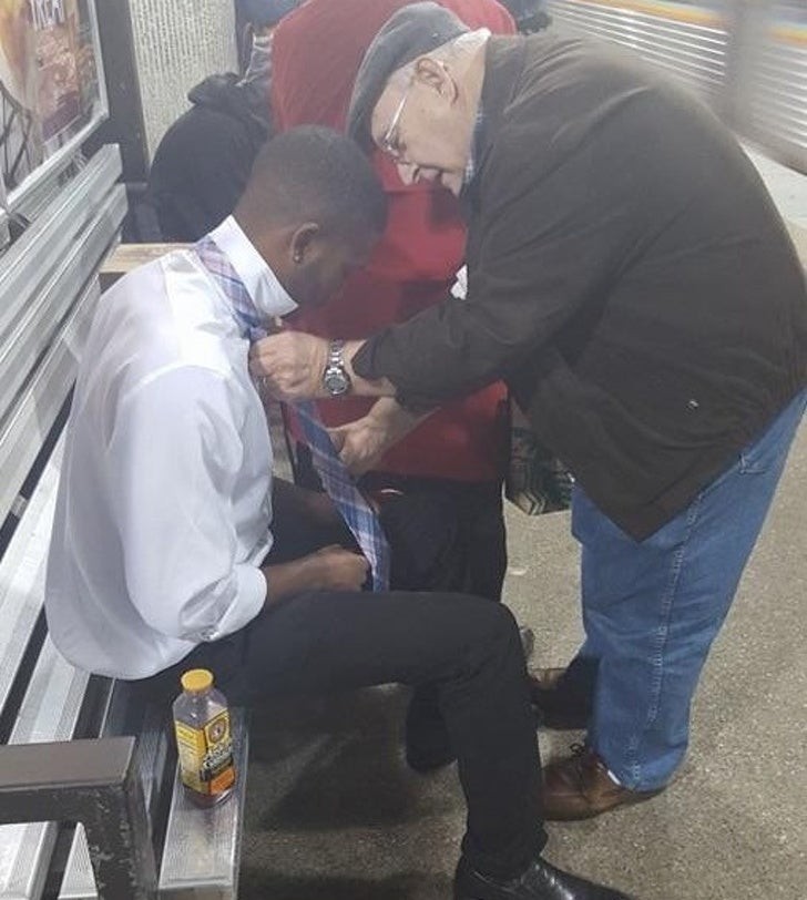 3. Un vieil homme aide un jeune homme à nouer une cravate.