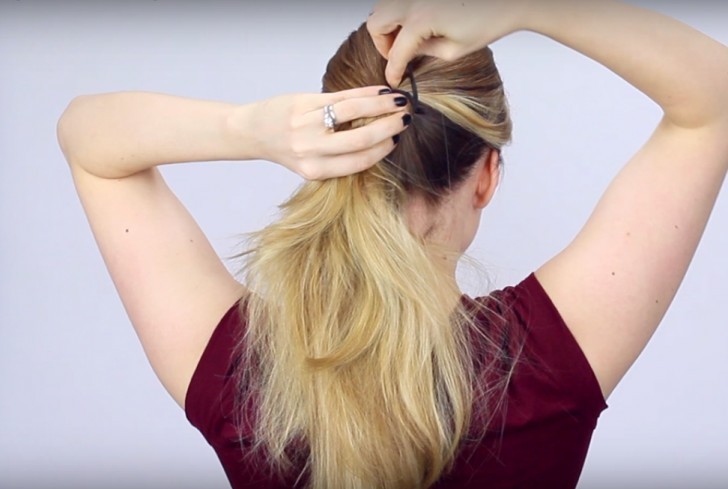 4. Tenete insieme le due ciocche di capelli e agganciate un'estremità dell'elastico ai capelli, avvolgetelo intorno a entrambe le ciocche e chiudete con il secondo gancio