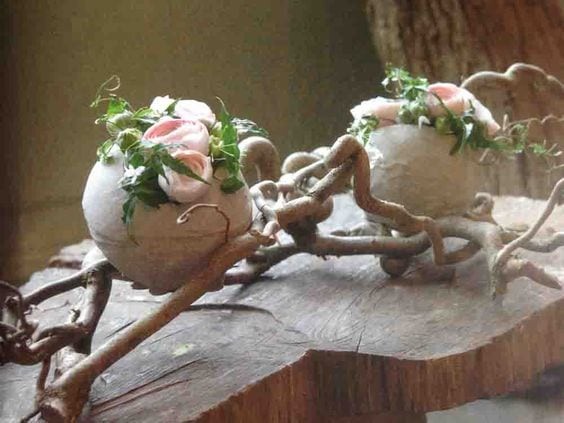 1. Sfere decorate con fiori e adagiate tra rami di nocciolo contorto su una base di legno
