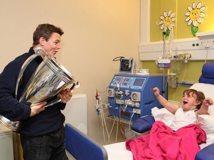 Der Rugby-Champion Brian O'Driscoll besucht einen kleinen Patienten im Krankenhaus und bringt sogar den Pokal mit.