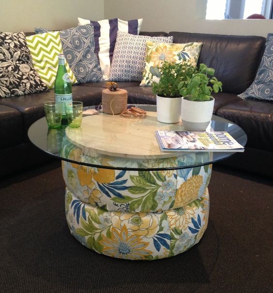 6. Un tavolino più sofisticato: due gomme coperte con stoffa colorata e un ripiano di vetro che si poggia su un cerchi di legno