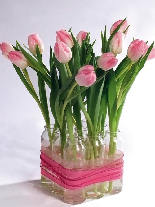 7. Riciclate vasetti di vetro e teneteli legati insieme come in foto per ospitare tanti fiori: è un modo diverso dal solito ma molto bello