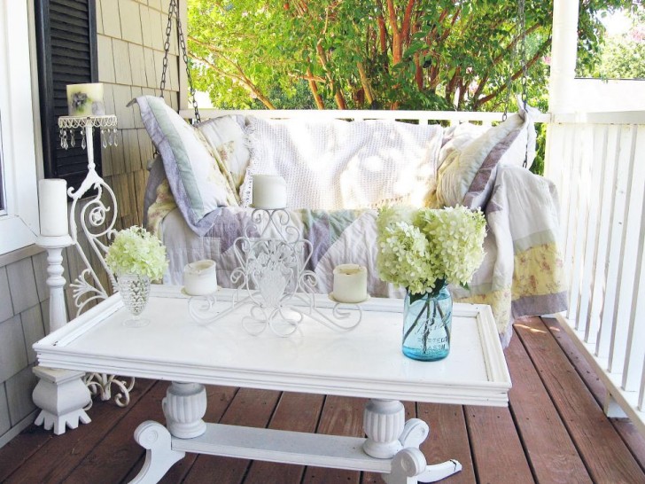 2. Un patio decorato con tavolino dalle modanature vintage, un divano-dondolo, oggetti di ferro battuto e colori tenui e luminosi