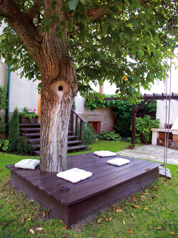 14. Una bella postazione sotto un albero, costruita con assi di legno e ridipinta per essere in tinta con il resto del giardino