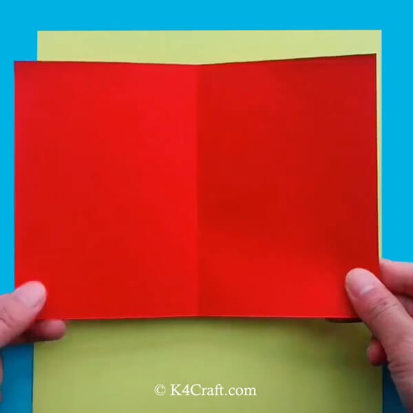 1. Sistemate il fondo giallo sul tavolo di lavoro e poi prendete un quadrato rosso più piccolo e piegatelo a metà