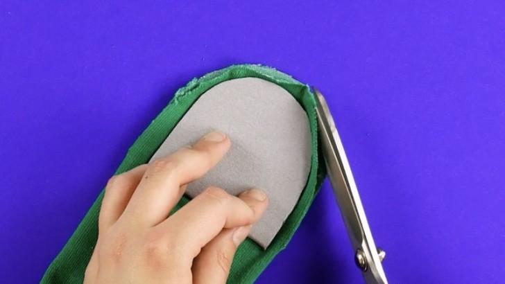 3. Appoggiate il ritaglio piegato sulla punta del calzino appiattito sul piano di lavoro e tagliatene i bordi come in foto