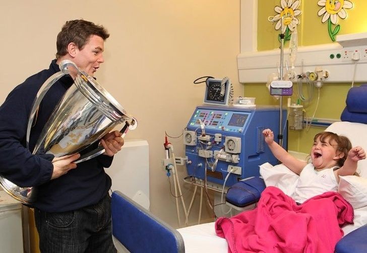 Brian O'Driscoll, former captain of the Ireland rugby team, visit a sick girl in the hospital after winning the Heineken trophy