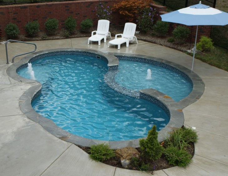 1. Una piscina con due aree di profondità diverse e una forma irregolare curva, circondata da una pavimentazione a lastre grandi