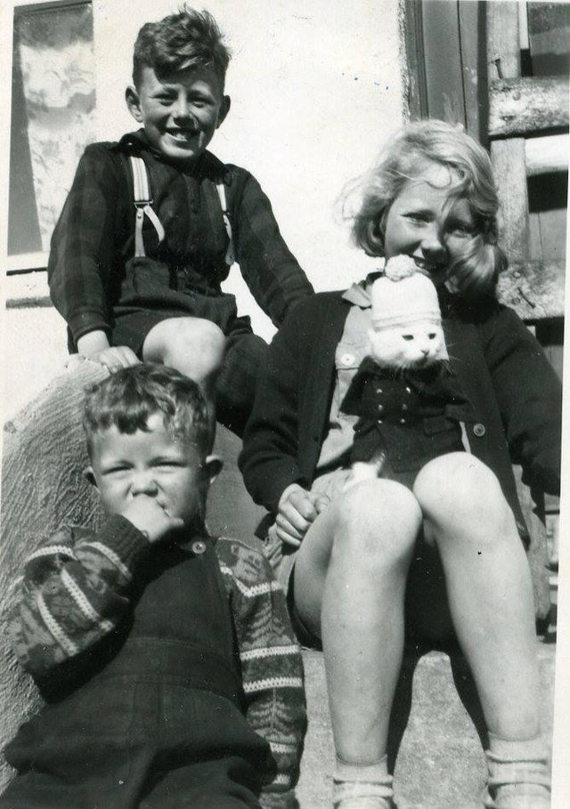 Vergnügte Kinder, nachdem sie ein Kätzchen verkleidet haben (um 1950).