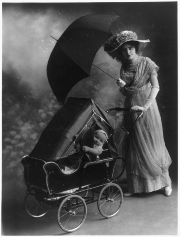 6. Eine Frau schiebt einen für Regen ausgerüsteten Kinderwagen 
