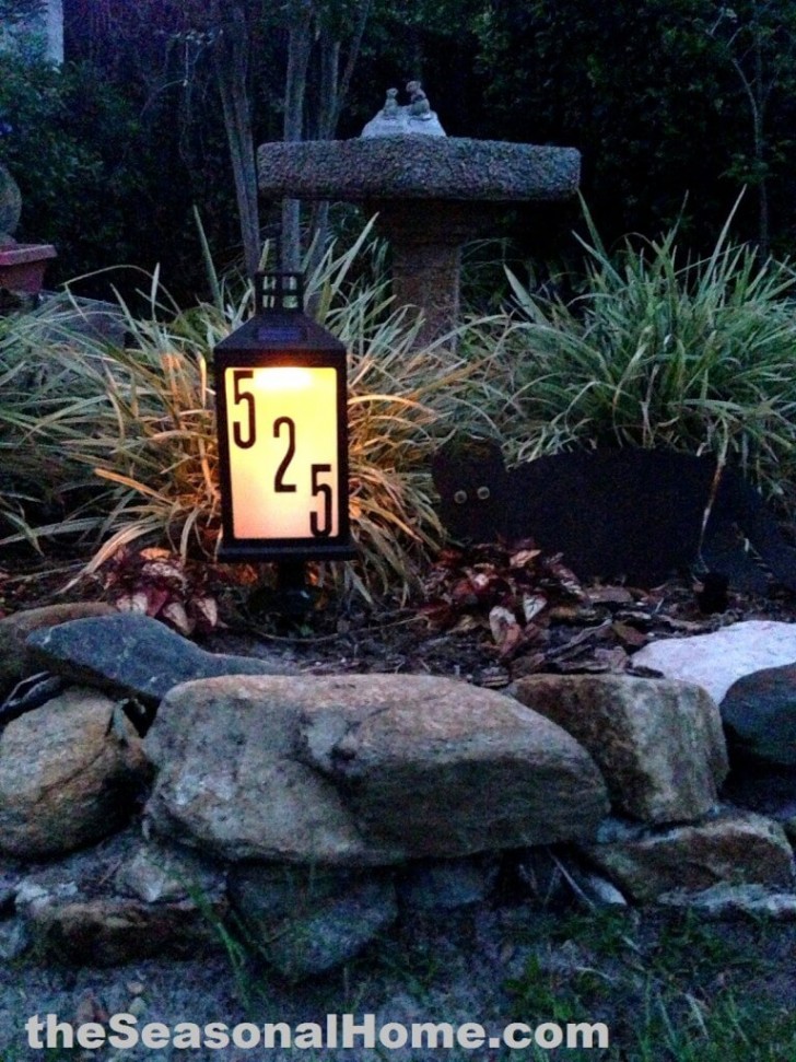 2. Een lantaarn met het huisnummer die bezoekers verwelkomt in een bloemenperkje voor het huis