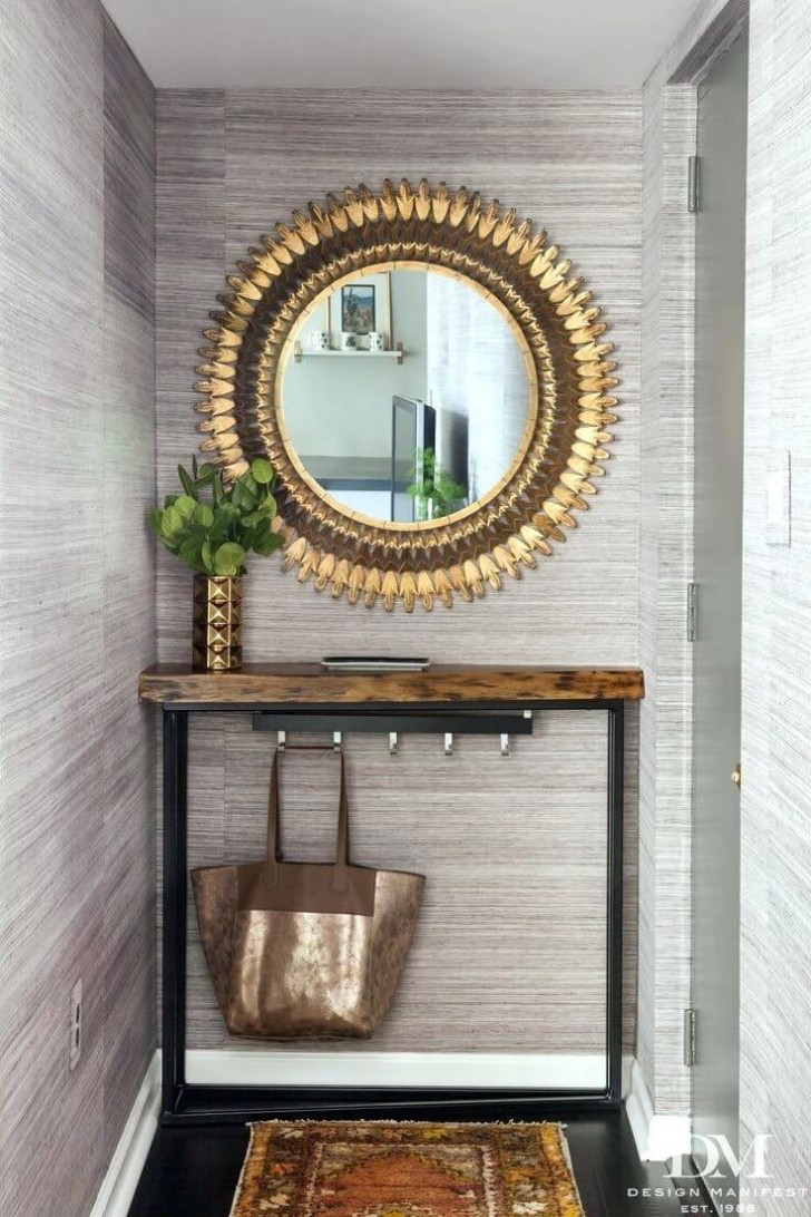 12. In un ambiente grigio con mobili in legno e metallo questo specchio dalla vistosa cornice dorata è l'unica decorazione che serve, richiamata dal vaso. Non mancano comodi ganci per appendere borse
