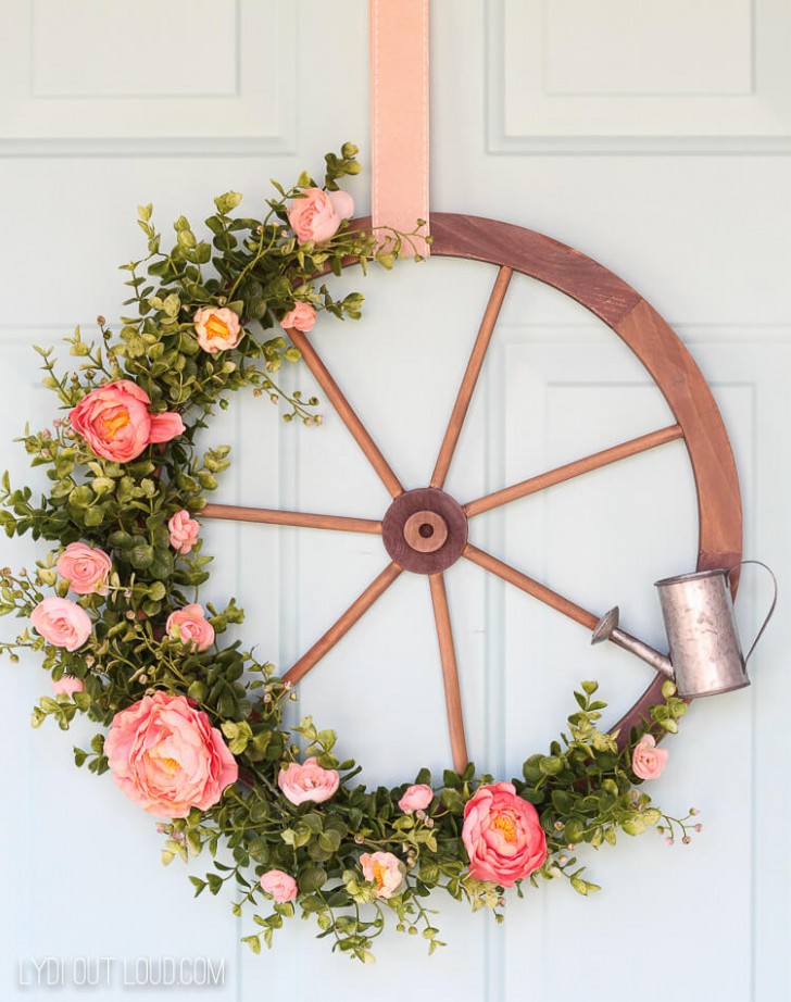 1. Una ruota di legno che ricorda quelle dei carri, decorata solo su un lato con tante rose finte e un piccolo innaffiatoio di metallo