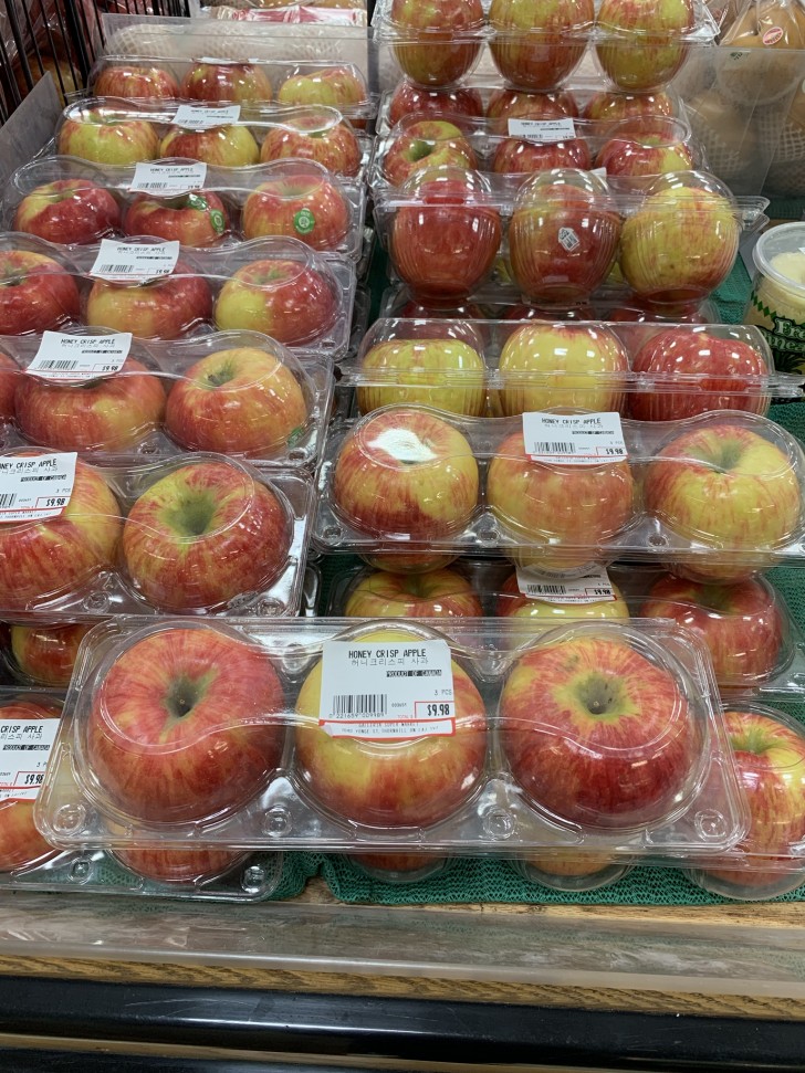 Un tris di mele confezionate in apposite vaschette di plastica. 