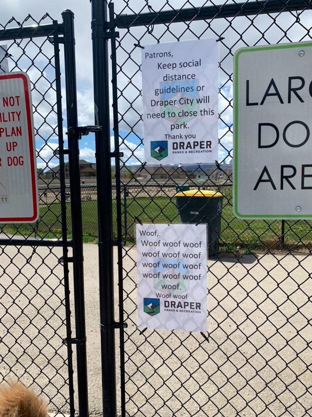 Ein Schild erinnert an die soziale Distanzierung am Eingang zu einem Hundetagesbereich: unten die Übersetzung für Hunde.