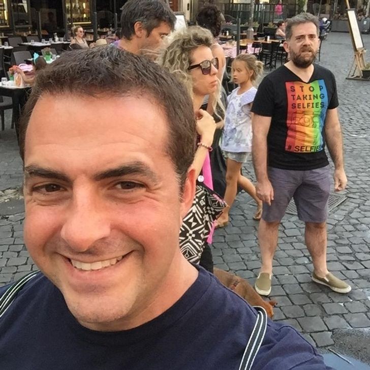 La camiseta del hombre de atrás dice: "Deja de hacer selfie". ¡Que ironía de la suerte!