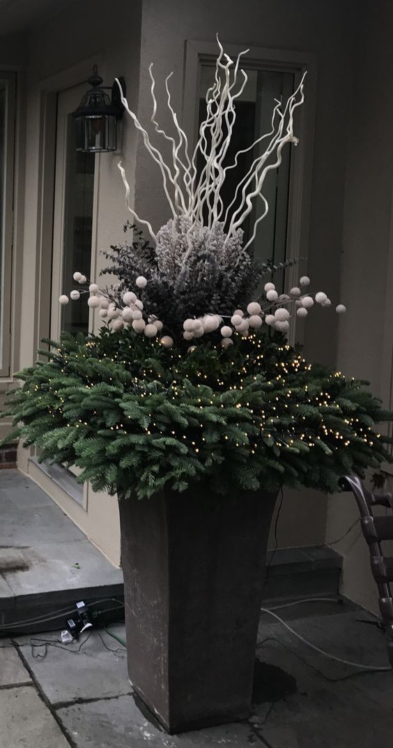 3. Een imposant kerststuk in een grote hoge plantenbak bij de voordeur