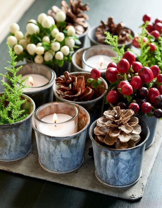 9. Una vassoio con vecchi stampini per dolci, ognuno riempito con candele o pigne e altri elementi verdi