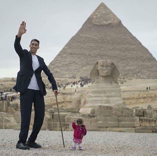 11. L'uomo più alto del mondo e la donna più bassa del mondo posano in una foto in Egitto, davanti alla Sfinge e alle Piramidi
