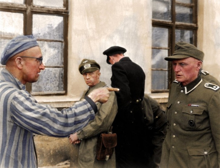 19. Un prigioniero russo che punta il dito contro una guardia nazista nel campo di Buchenwald