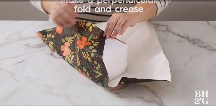 2. Neem een hoek van het papier en wikkel het om het pakje heen zodat je een diagonaal maakt