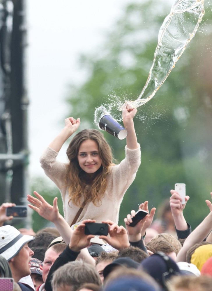 14. En fest eller en konsert, händerna upp och en glad blick. Tjejen har ännu inte sett att ett glas är på väg i hennes riktning.