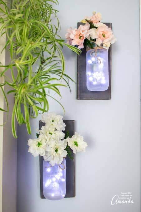 5. Met grijs geschilderd hout, witte bloemen en een ondoorzichtige pot krijgen deze meestal rustieke wandlampen een modernere en geraffineerd uitstraling
