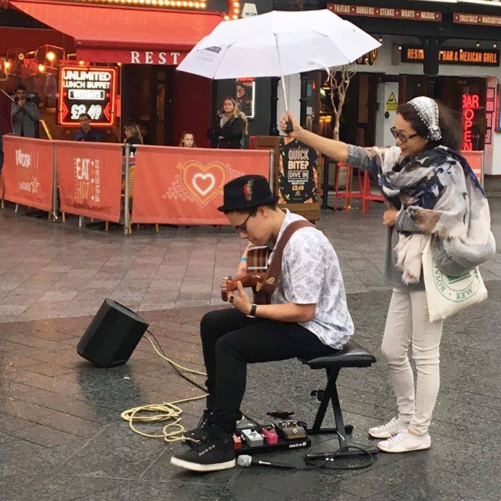 12. Een muzikant wilde niet stoppen met muziek te spelen door de regen en een vrouw schoot hem te hulp.