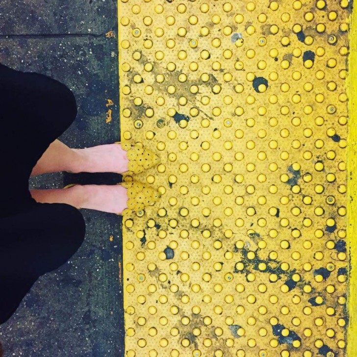 16. Les pointes des chaussures de cette femme correspond parfaitement, par sa forme et sa couleur, à la ligne jaune de la plateforme.