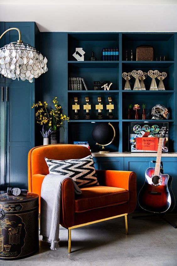 8. Su questo sfondo blu intenso che crea uno spazio intimo e rilassante, la poltrona arancione è un tocco vivace che non altera l'atmosfera della stanza