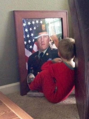 Dieser kleine Junge schaut gerade zärtlich auf das Bild seines Papas, der im Krieg als Soldat gefallen ist....