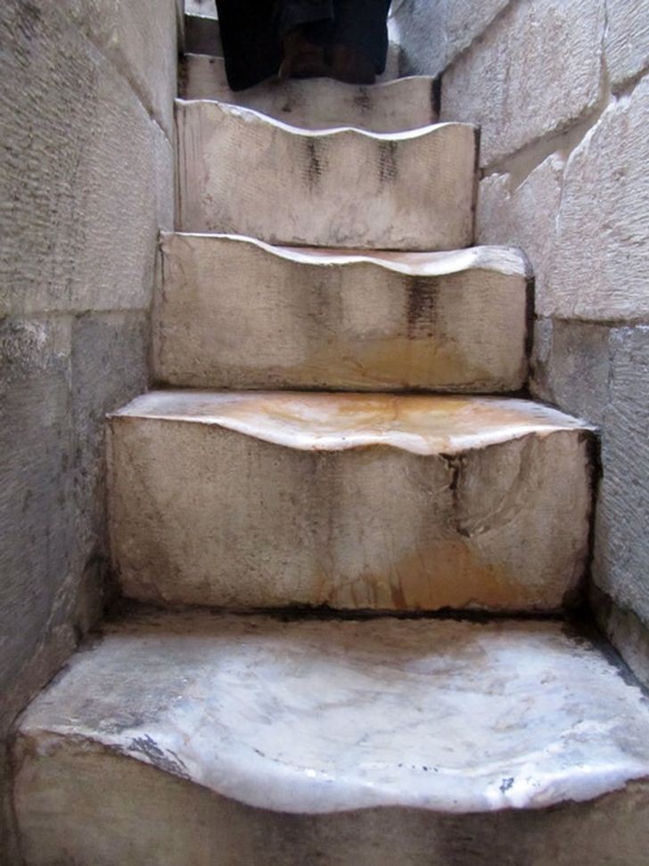 Kijk eens hoe versleten de oude trappen zijn die toeristen elk jaar naar de top van de toren van Pisa brengen!