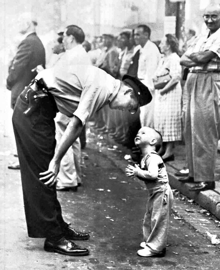 Immagine d'altri tempi: siamo nel 1958 e un poliziotto gentile spiega ad un bimbo che non può attraversare la strada per via della parata in corso!