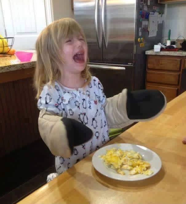 She's crying because she can't hold her fork with those oven mitts on!