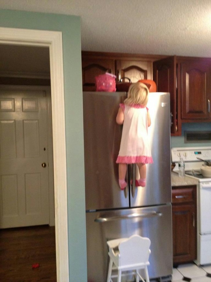 O que minha filha está fazendo para pegar o doce que está em cima di refrigerador...