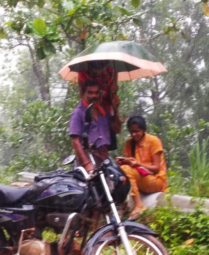 Ce père tient un parapluie pour sa fille afin qu'elle puisse suivre ses cours en ligne sous la pluie - 1