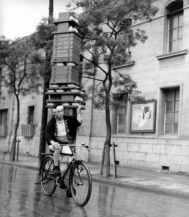 1935. Un jeune livreur livre des nouilles traditionnelles soba à Tokyo. Les cyclistes avaient l'habitude de porter de grandes piles de vaisselle sur leurs épaules en faisant du vélo.
