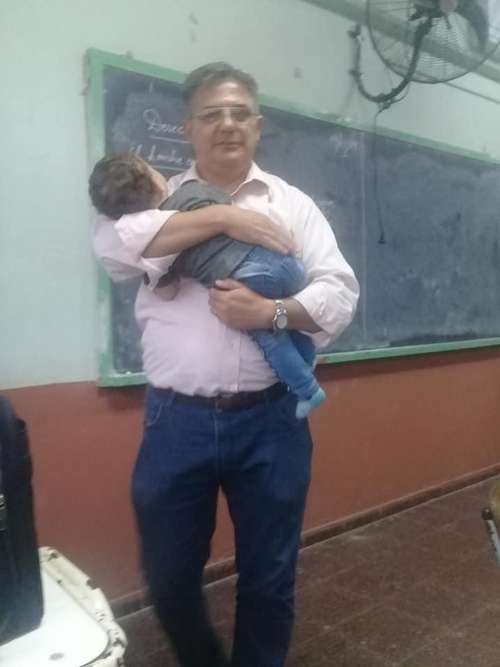 Profesor sostiene en sus brazos al hijo de una joven estudiante para que pueda seguir mejor la lección - 2