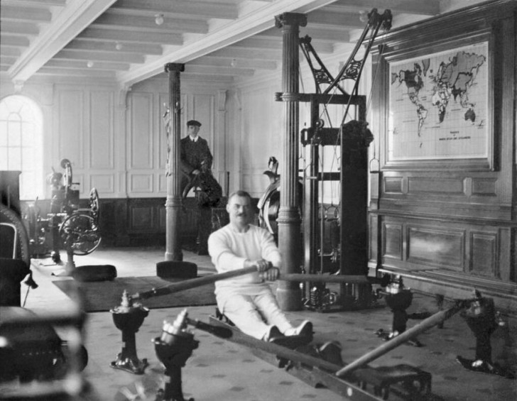 8. Un homme s'entraîne avec un rameur dans une salle de sport : nous sommes en 1912 et il est à bord du Titanic.