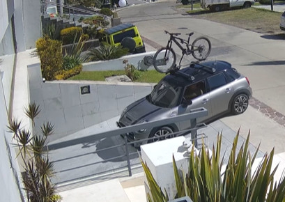 Met de fiets op het dak rijdt hij richting de garage