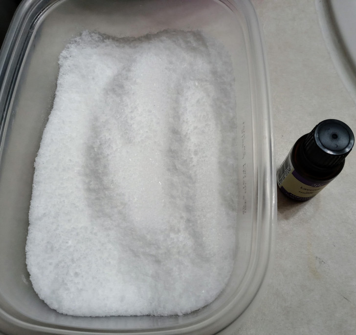 Una vaschetta di detersivo in polvere e una bottiglietta di olio essenziale